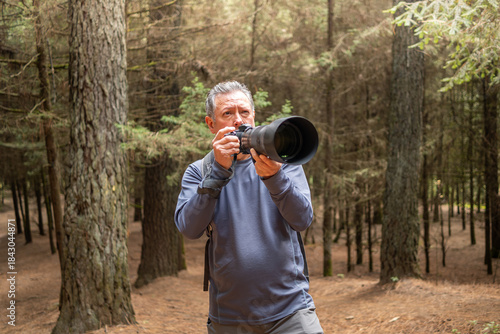 Senior man enjoying hobby in nature, birdwatching and wildlife photography