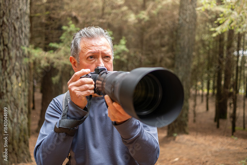 Senior man enjoying birdwatching hobby with camera and telephoto lens