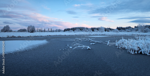 Frozen lake surrounded by snow under a cold winter sky. Quiet natural scenery with ice, frost, and seasonal atmosphere. West Lothian, Scotland