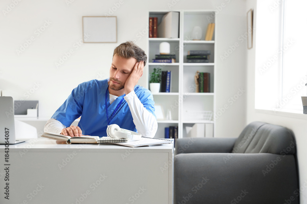 Obraz premium Male medical intern reading book at table in library