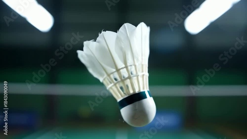 Cinematic slow motion close up of a badminton shuttlecock spinning in a seamless loop on a court.