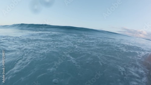POV. Surfer on black surfboard swimming in line up looking at big wave in Atlantic ocean during sunrise. Dominican Republic.
