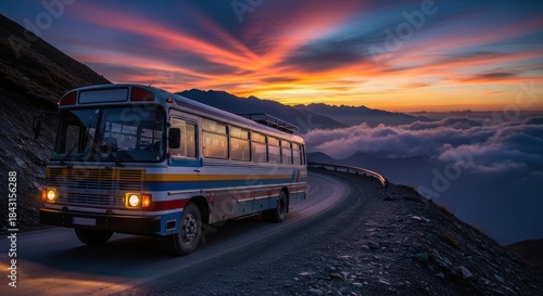 Fototapeta Naklejka Na Ścianę i Meble -  A vintage bus driving on a winding mountain road at sunset, with a colorful sky and clouds in the background.