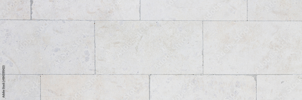 Naklejka premium The texture of the wall, lined with light stone blocks. The polished surface of the masonry. Wide panoramic texture for background and design.