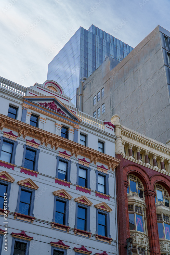 Fototapeta premium Detailed Facades of Classic Buildings Stand Tall Beneath Towering Glass and Concrete Modern City Structures