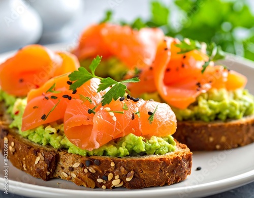 Close-up of two open-faced sandwiches with salmon and mashed avocado on toasted bread