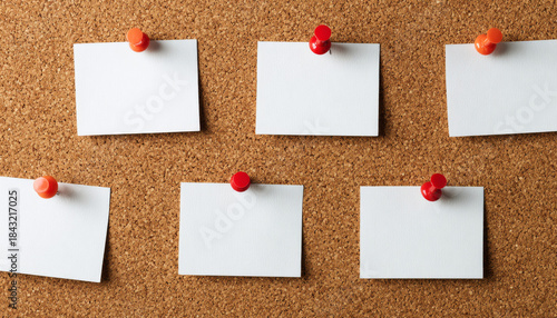 Blank white cards pinned on a cork bulletin board for notes or reminders