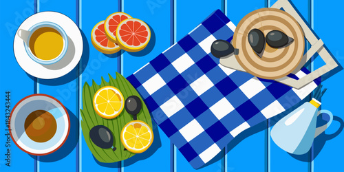 Overhead view of a vibrant summer picnic spread featuring citrus fruits tea and olives on blue stripes
