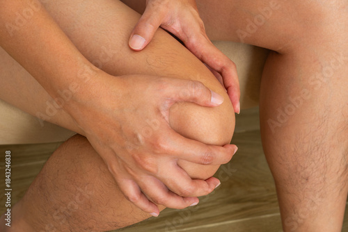 Fotografia Close-up of knee pain while seated—ideal for illustrating osteoarthritis, joint inflammation, or physical therapy treatment concepts