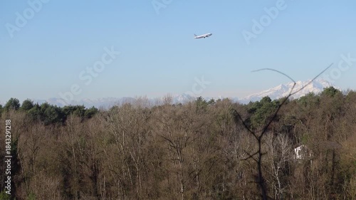 An aircraft flying far away during takeoff, captured against a scenic Himalayan landscape.
