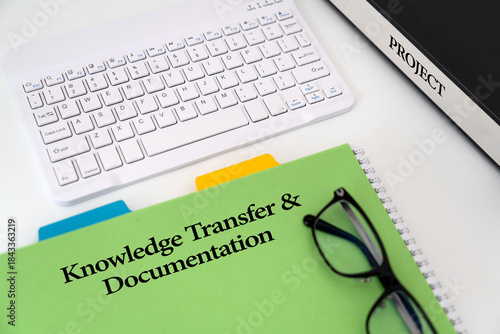 Illustrative Photo for 'Knowledge Transfer and Documentation' a project featuring green document titled ' Knowledge Transfer and  Documentation', a keyboard, glasses and binder labeled 'Project'