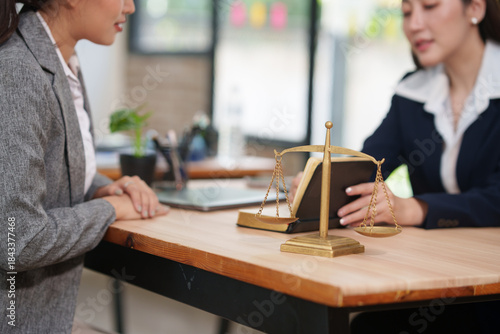 Female Lawyer Consulting Client with Scales of Justice in Office