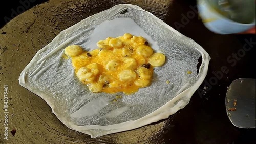 Footage of Vendor Putting Banana with Egg Fillings on a Dough for Cooking Sweet Roti