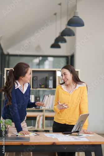 Asian businesswoman sitting at work using laptop talking and consulting in office