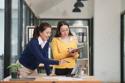 Asian businesswoman sitting at work using laptop talking and consulting in office