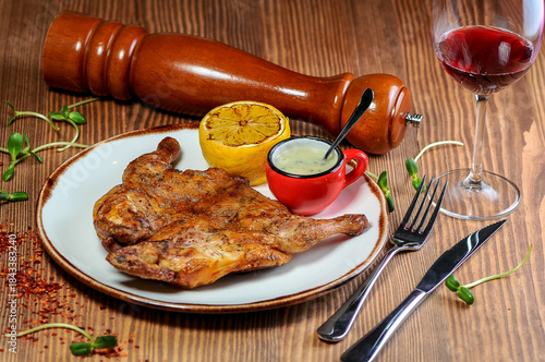 Roasted Tabaka chicken in a plate on the table with wine and spices