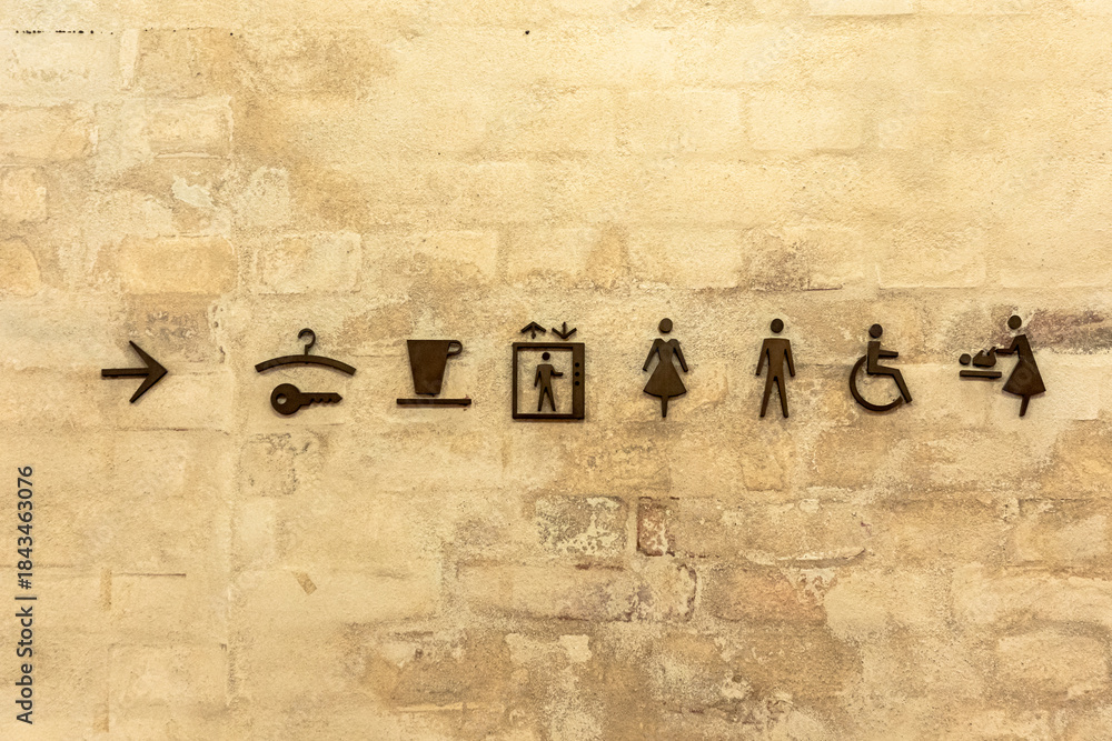 Obraz premium Set of facility icons on a brick wall indicating restroom, accessibility, and elevation signs