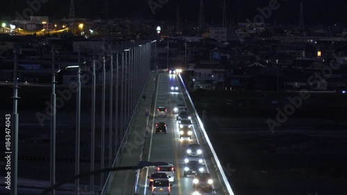 河川にかかる橋の上を車が走る夕方から夜の風景
