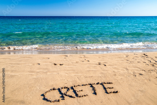 Fototapeta Naklejka Na Ścianę i Meble -  Create word made of stones on sandy beach by turquoise sea at Mazida Ammos, Crete, Greece