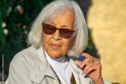 Elegant Senior Woman with White Hair Wearing Sunglasses Outdoors