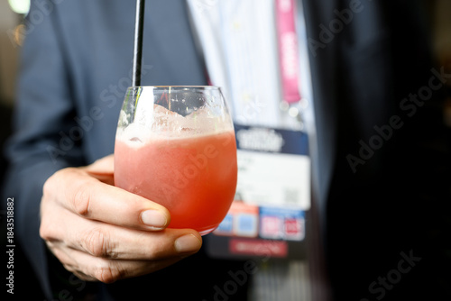 Person holding pink cocktail in glass at professional event