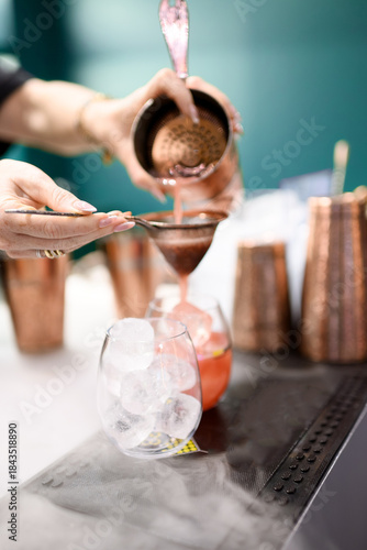 Bartender Using Copper Tools to Pour Red Cocktail