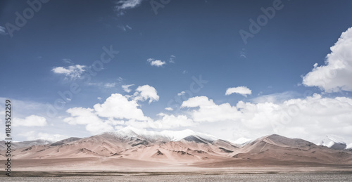 Landscape in the Pamir Mountains of Tajikistan with snow, glaciers, and cliffs, a panorama of mountains in cloudy weather for the background, nature in the Tien Shan highlands, landscape background