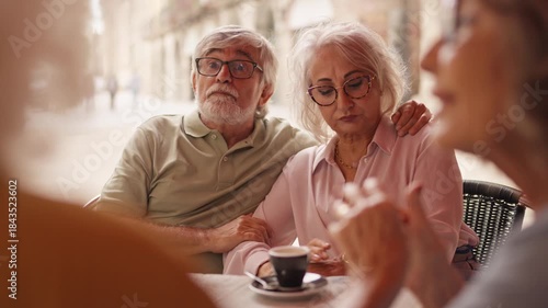 Senior friends talking and drinking coffee at an outdoor cafe