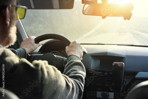 Men’s driver's hand holding steering wheel of car while driving.