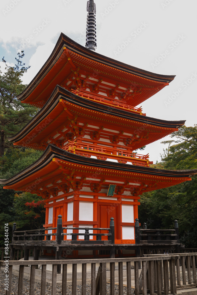 Obraz premium Kyoto.Three-Tier Japanese Pagoda Temple in Autumn Garden Setting with Red Wood and Stone Fence