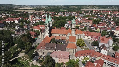 Aerial view of Naumburg’s historic center with Naumburg Cathedral in the foreground, surrounded by rolling hills and vineyards in the background.