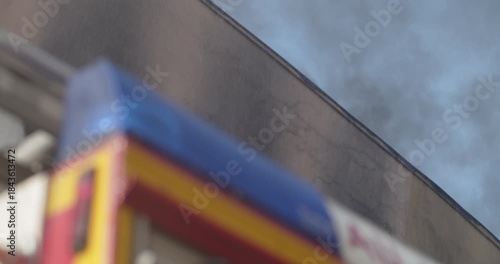 Drops of water gun falling between the flashing light of the fire engine blurred, and the burning building with black smoke in the background.
