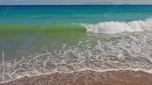 Beautiful view of Aegean Sea waves washing pebbled beach with gentle water on background. Greece.