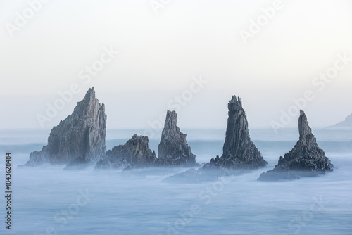 Photograph of the iconic rock formations of Gueirua Beach in Asturias, with a seagull perched on one of the sharp sea stacks. A timeless coastal scene highlighting texture, contrast, and solitude.