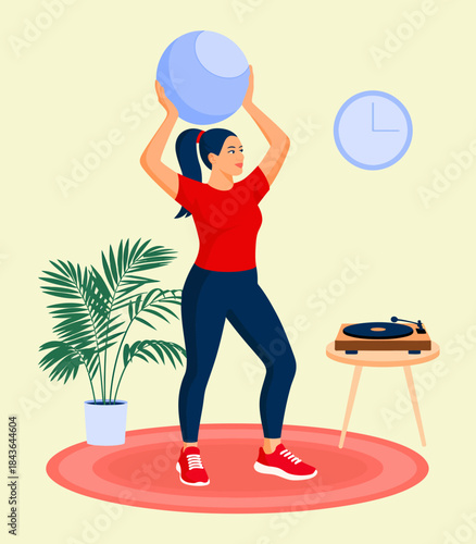 A woman is energetically holding a fitness ball in a relaxed home environment, showcasing an active lifestyle intertwined with comfort and enjoyment in daily routines.