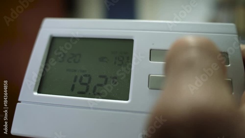 Caucasian man adjusting the the wireless thermostat , adjusting the room themperature on a cold winter day.