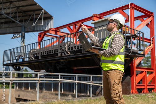Field engineer using laptop to monitor hydraulic water control facility operations at outdoor industrial site
