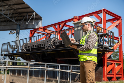 Field engineer using laptop to monitor hydraulic water control facility operations at outdoor industrial site