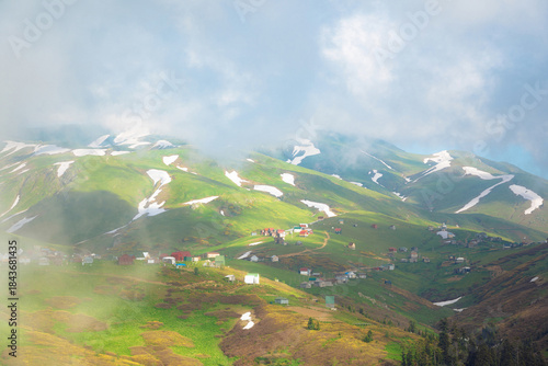 Aerial view of Gomis Mta in Georgia, a mountain village with small wooden houses surrounded by snow and green hills. Peaceful and scenic highland landscape