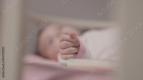 Baby's tiny hand is in focus in a crib