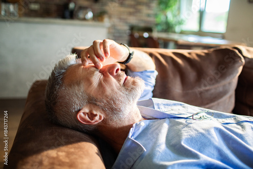 Foto Senior man feeling exhausted resting on sofa at home