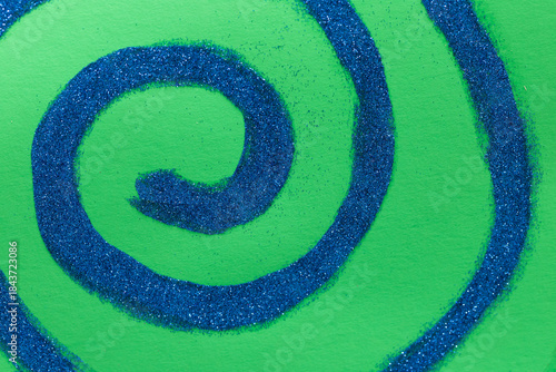 Blue glitter spiral on green paper