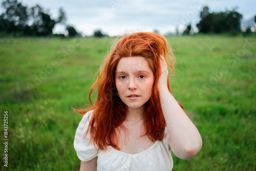 Natural portrait of redhead woman in green field