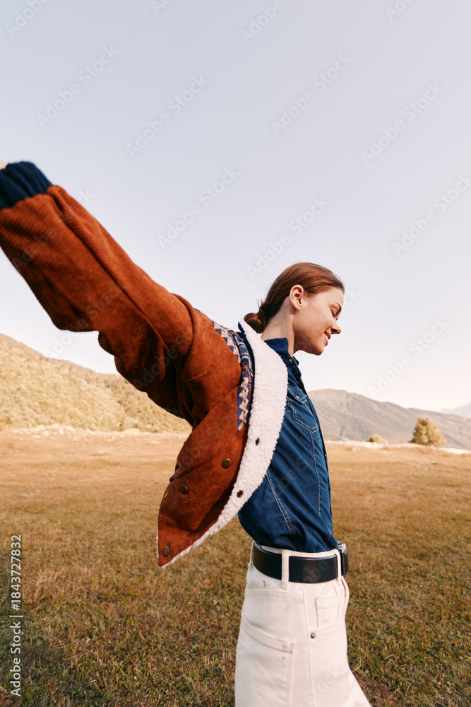 Fototapeta premium Woman in jacket in a field outdoors, portrait with smile and sense of freedom in the countryside. Happy nature lifestyle, denim shirt and warm coat captured in joyful motion.