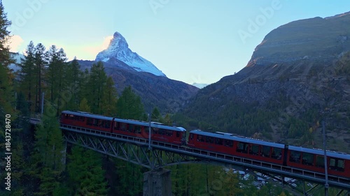 Rack Railway Red Train on Findelbachbrucke Bridge, Matterhorn Mountain and Larches in Autumn Evening. Swiss Alps. Aerial Drone Shot. Zermatt, Valais, Switzerland