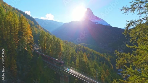 Rack Railway Red Train on Findelbachbrucke Bridge, Matterhorn Mountain and Larches in Autumn Evening. Swiss Alps. Aerial View. Zermatt, Valais, Switzerland