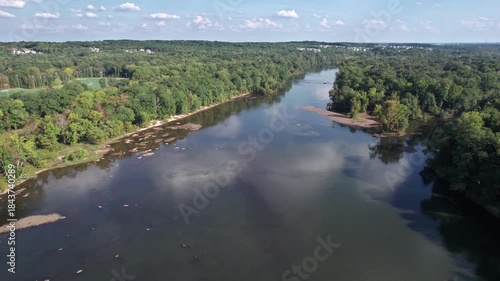Aerial push over slow moving Catawba River with distant suburbs