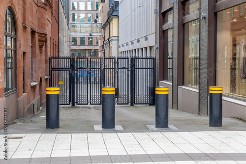 Foto Row of Black and Yellow Security Bollards in Front of a Metal Gate