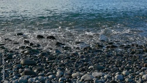 waves of the Atlantic Ocean splashing on a pebble beach in Madeira, Spain