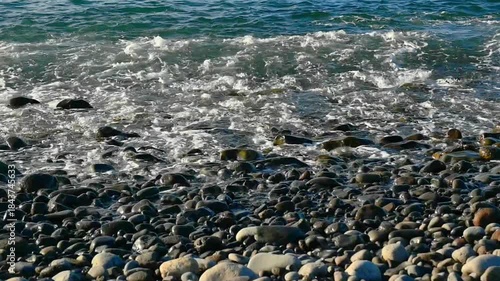 waves of the Atlantic Ocean splashing on a pebble beach in Madeira, Spain